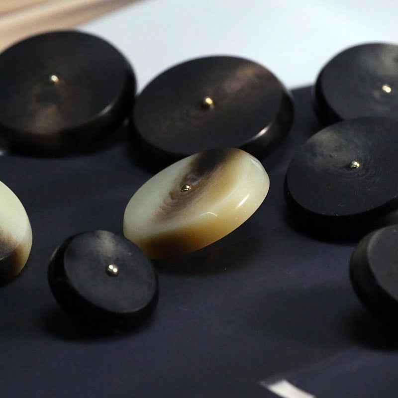 Assorted round resin buttons in black and khaki with metal shanks, close-up