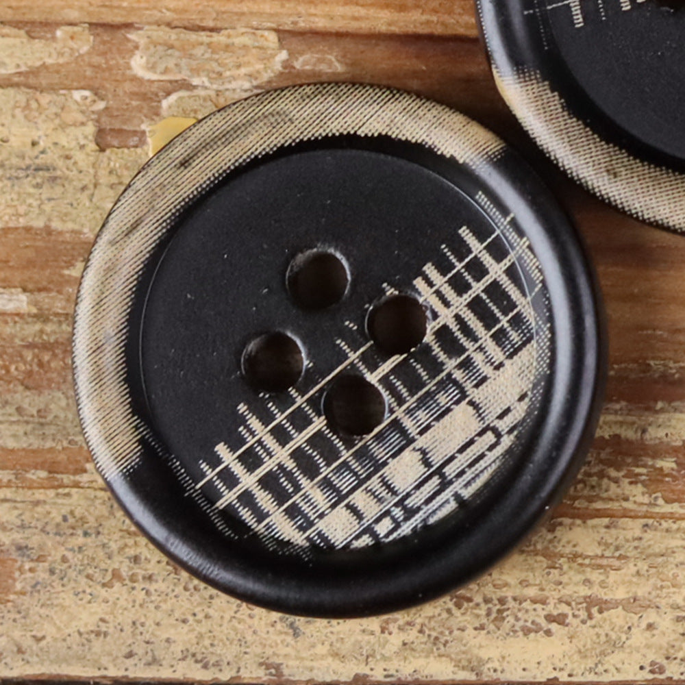 Close-up of a 4-hole round button with plaid fabric pattern on a dark face