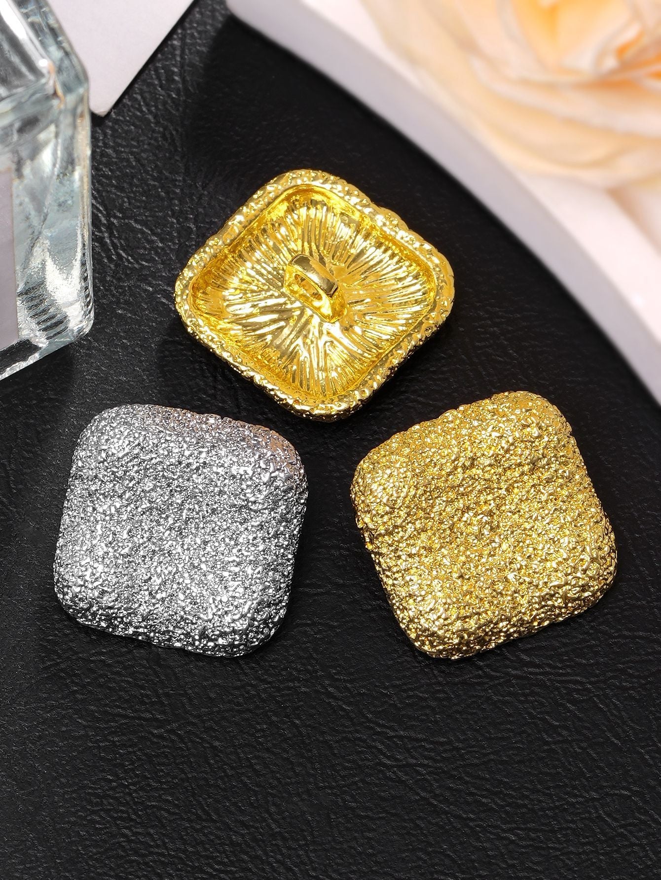 Square textured metal shank buttons in gold and silver, close-up