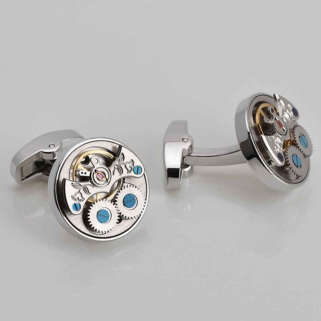 Manschettenknöpfe mit offenem Tourbillon-Motiv, blauen Akzenten, rundes Metallgehäuse silber.
