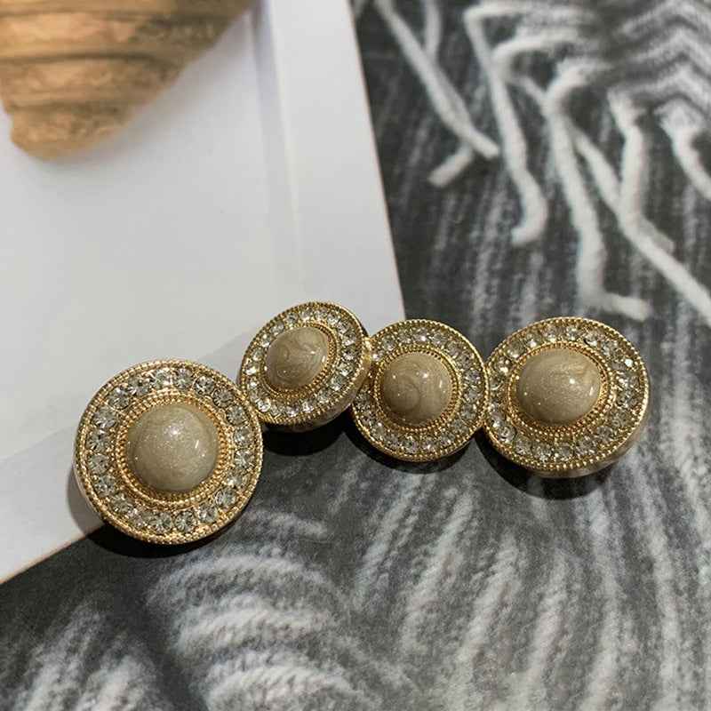 Round gold-tone button with rhinestone trim and light beige center, front view