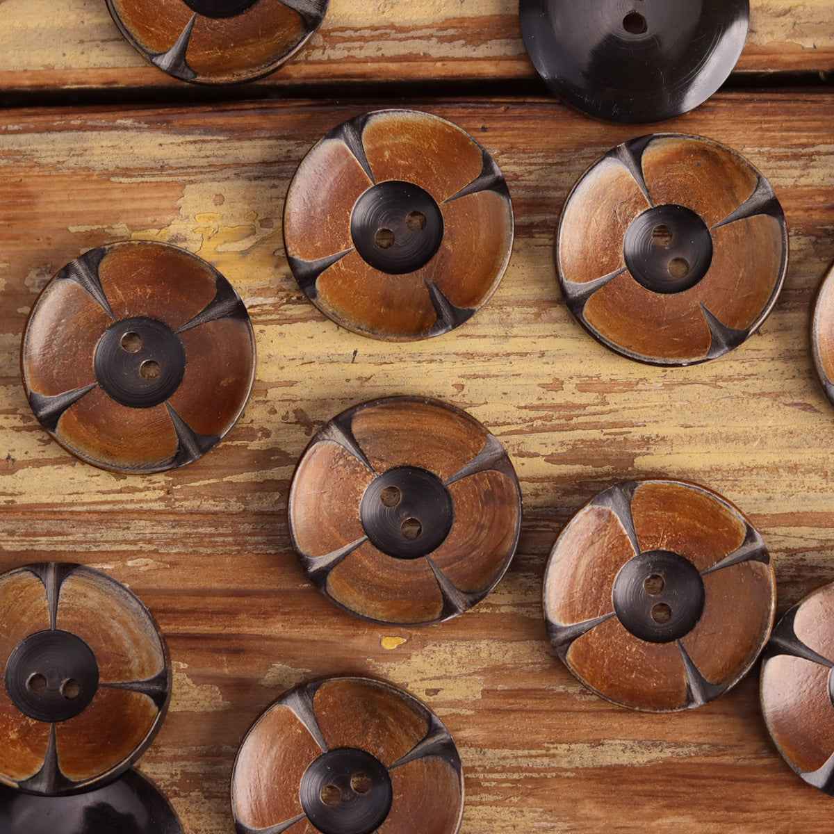 Round 2-hole horn buttons with carved floral pattern, mustard-toned faces and dark centers