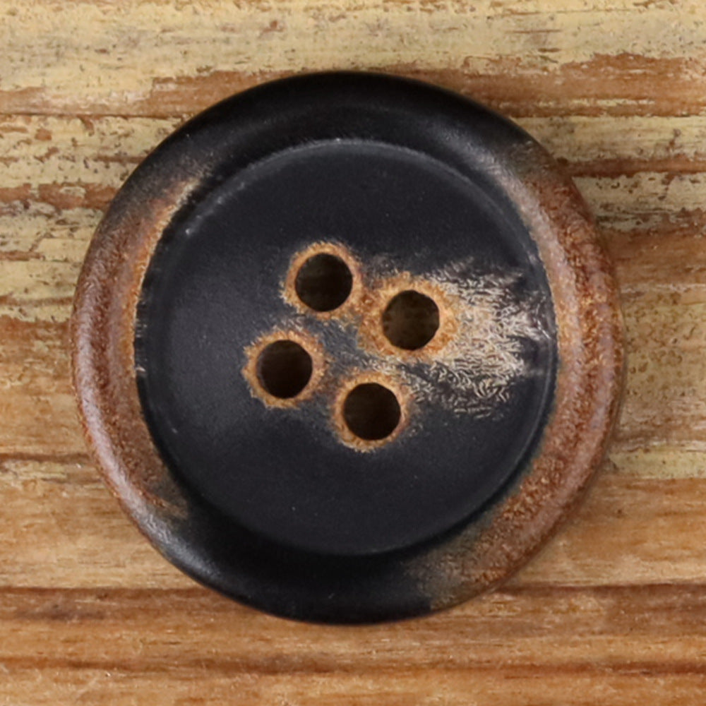 Close-up of a 4-hole round button with warm brown ring around the holes on dark face
