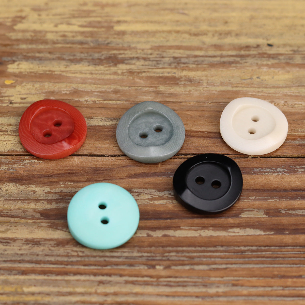 Round 2-hole buttons in red, gray, white, turquoise, and black on wood