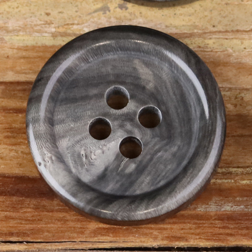 Close-up of a 4-hole round button with grayish marbled texture and four holes