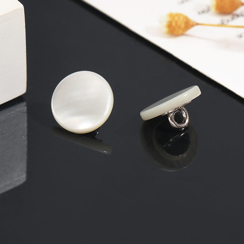 White shell shank button front with visible metal shank, round pearl finish