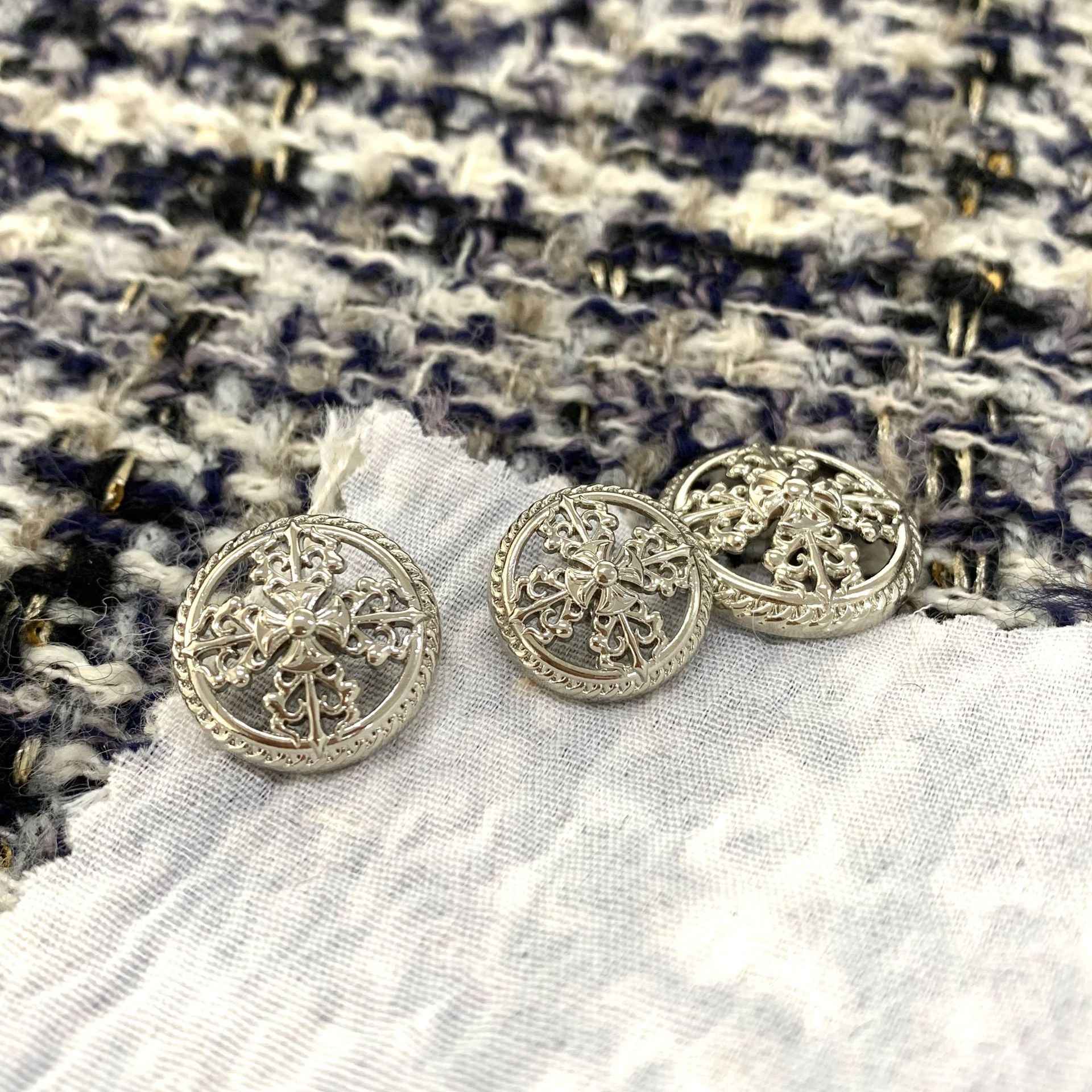 Round silver vintage hollow cross metal shank buttons, ornate border, angled view
