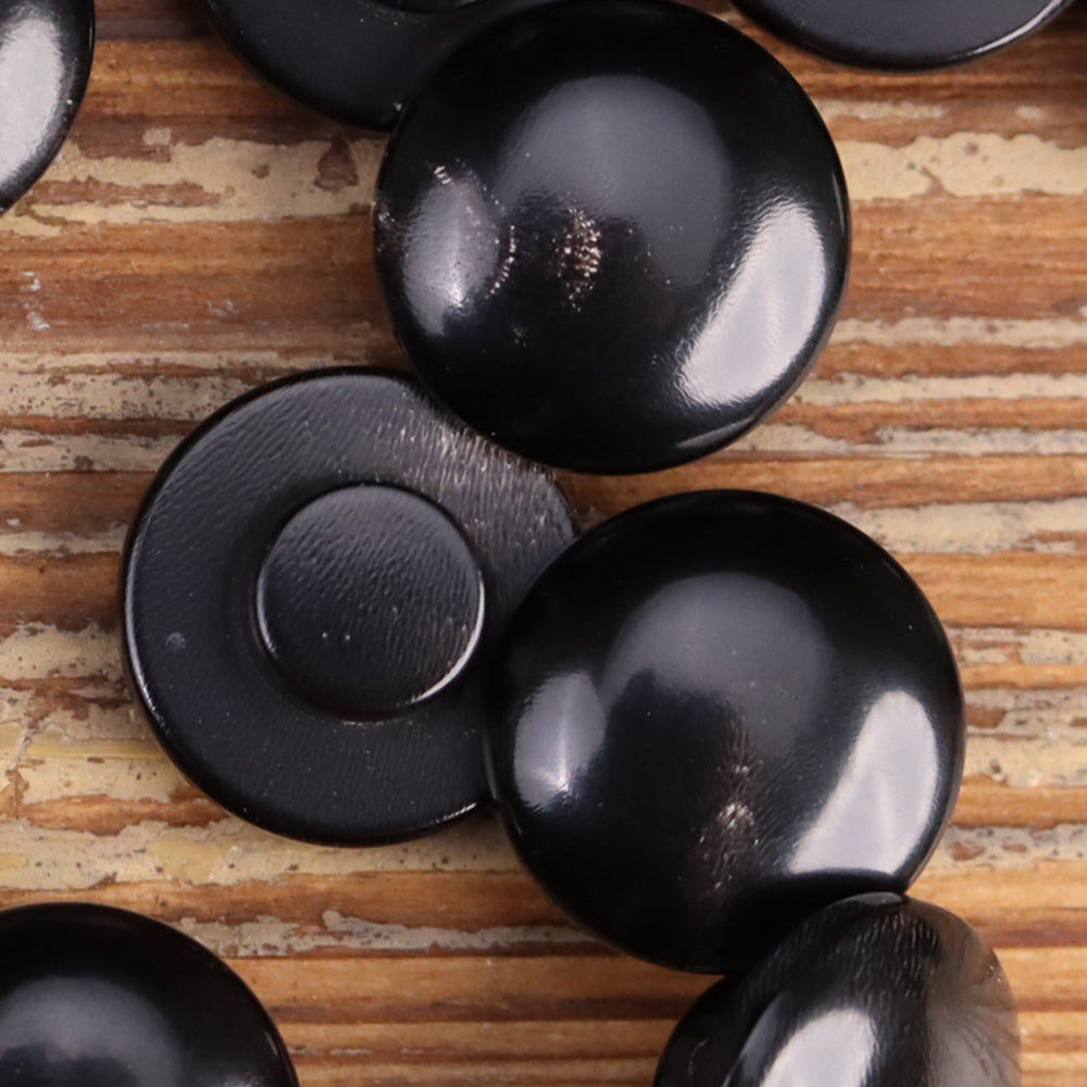 Multiple round horn buttons in black, showing domed fronts and underside backs
