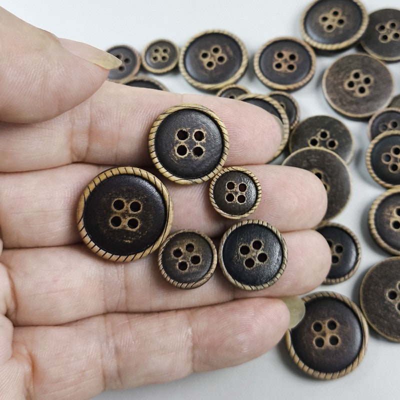 Hand holding round 4-hole dark brown buttons with tan stitched edges