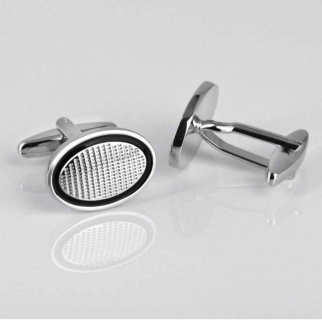 Black oval cufflink with silver oval frame and textured white perforated face