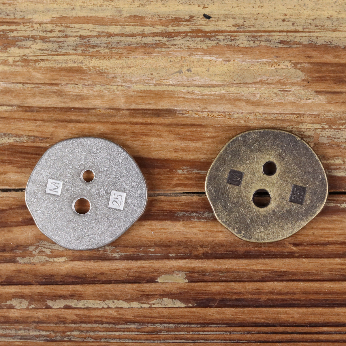 Irregular metal 2-hole buttons, silver and bronze, with two holes and stamped marks.