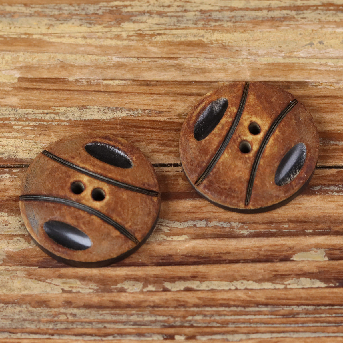 Handmade horn button pair, round with black oval detail and two-hole edging