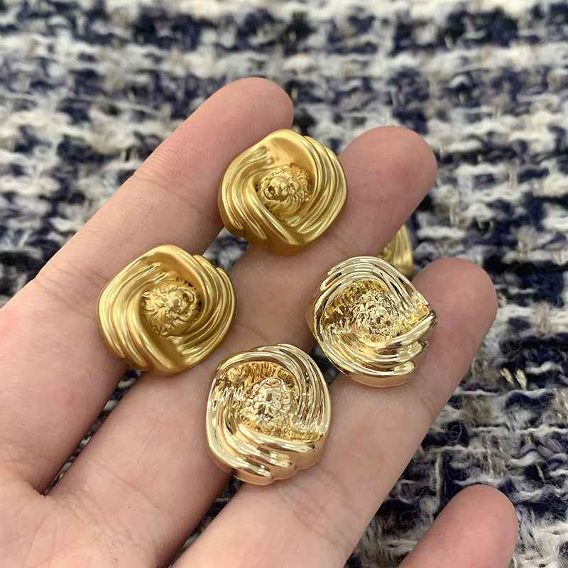 Goldene Löwenkopf-Metallknöpfe in der Hand, unregelmäßige Optik mit geriffeltem Rand