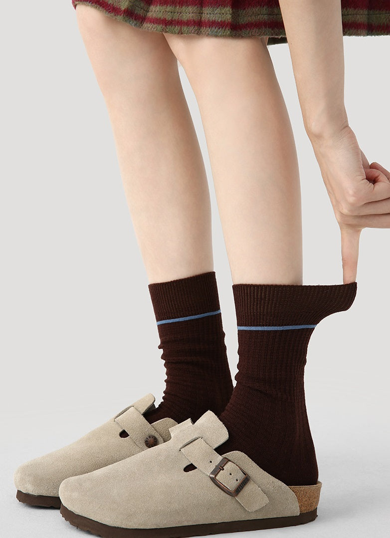 Dark brown crew socks with blue contrast cuff on model’s legs