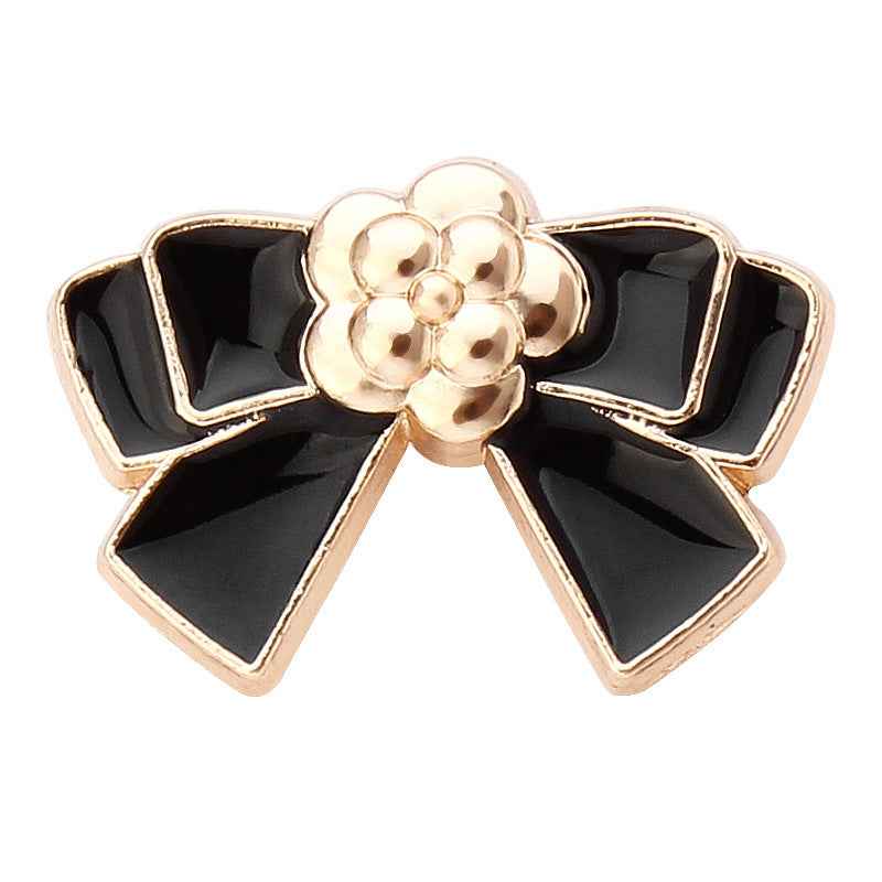 Gold-and-black bow tie metal button with flower center, scalloped ribbon design
