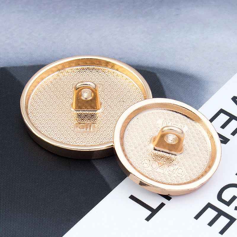 Back view of round alloy shank button with gold-tone prong and stamped center
