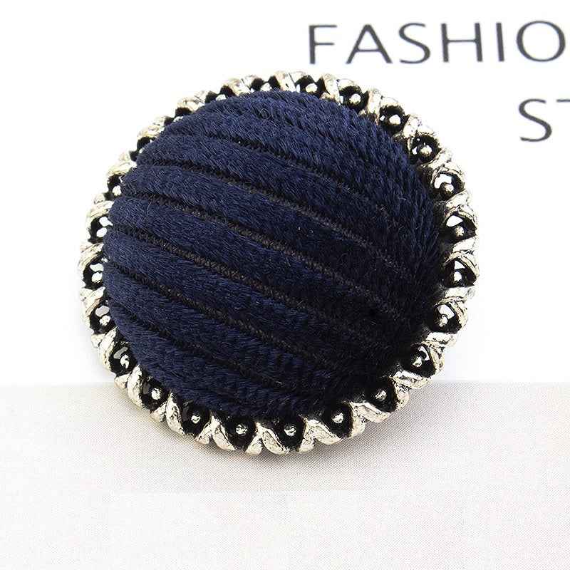 Dark blue velvet-wrapped metal button with lace-edged scalloped rim and ribbed texture