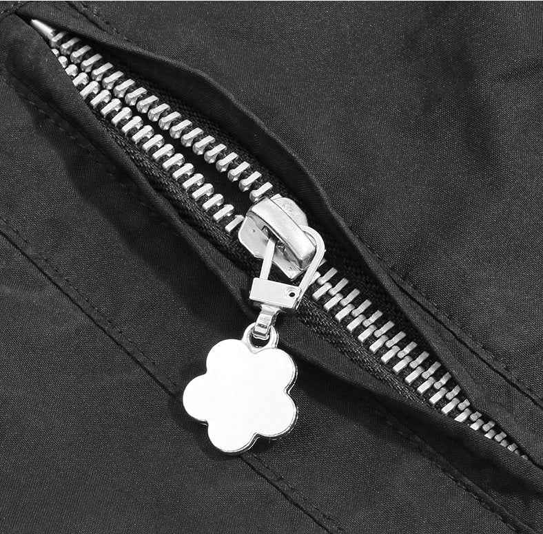 Flower-shaped zipper pull charm on black zipper, silver metal slider and loop