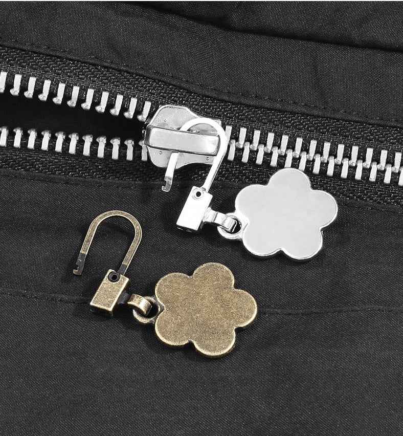 Zip pull charms with flower shapes: silver and gold tones on black fabric zipper