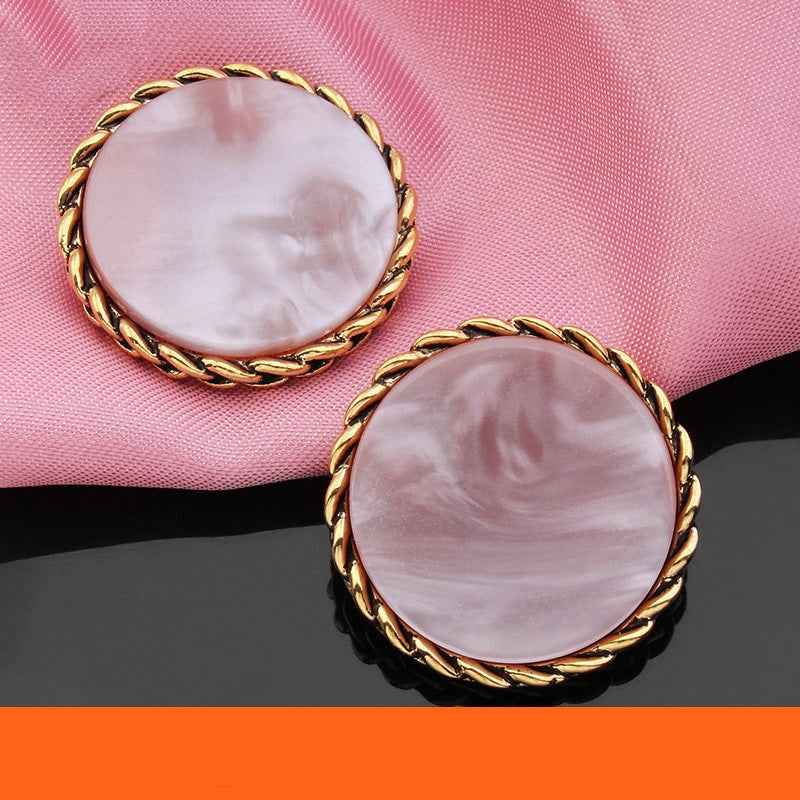 Two light pink round resin buttons with gold braided edge and marbled pearl finish