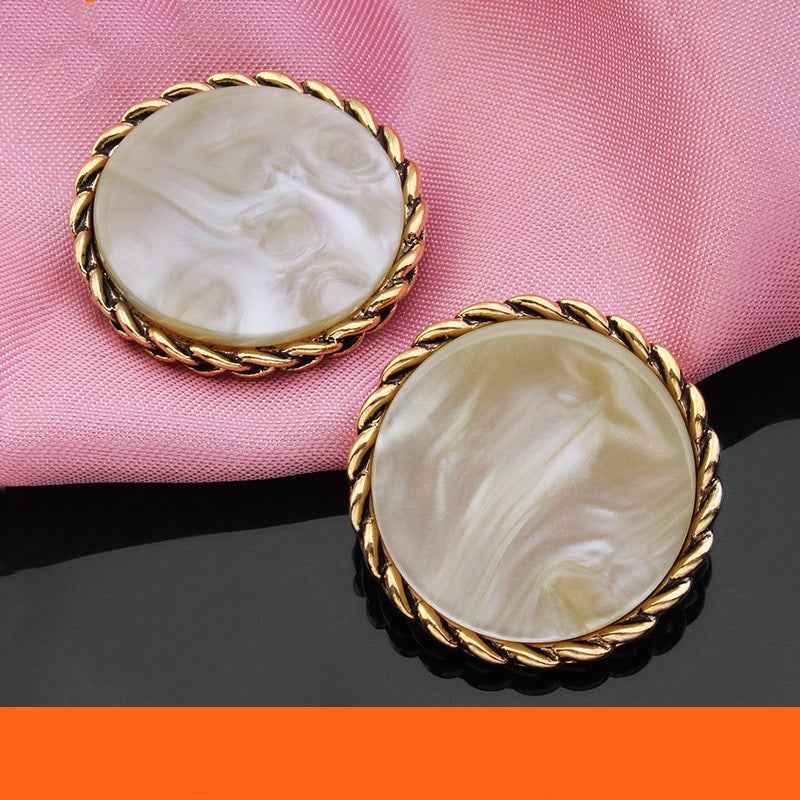 Two cream/ivory round resin buttons with gold braided edge and swirled marbled face