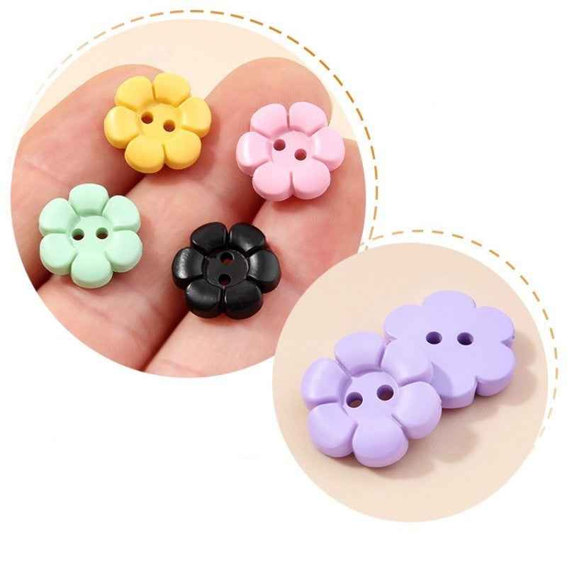 Close-up flower-shaped 2-hole plastic buttons in yellow, pink, black and lavender on hand
