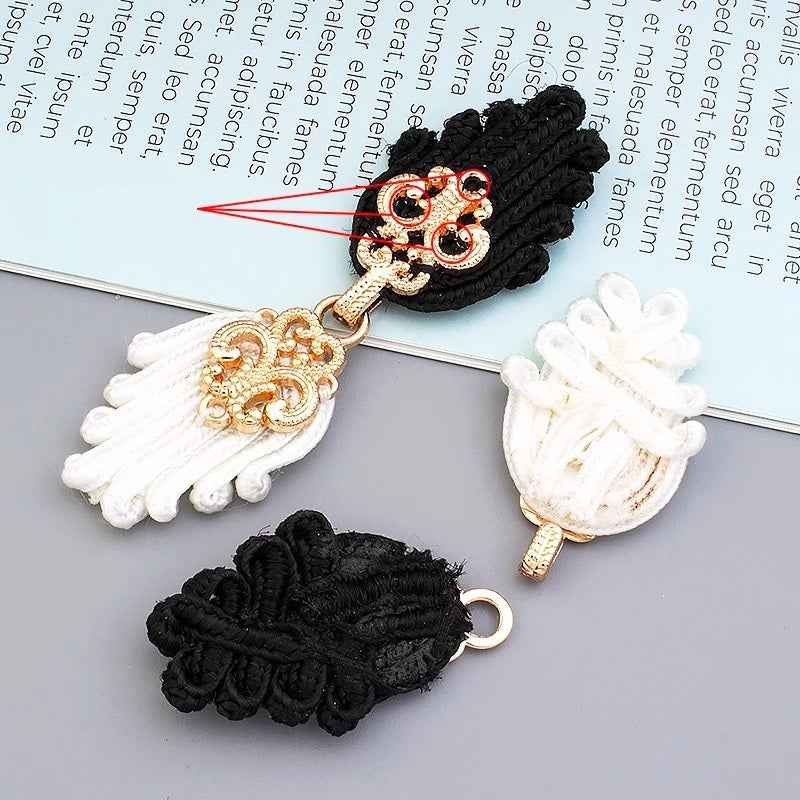 Black Chinese frog button pair with gold clasp and braided tassels; paired with white pieces