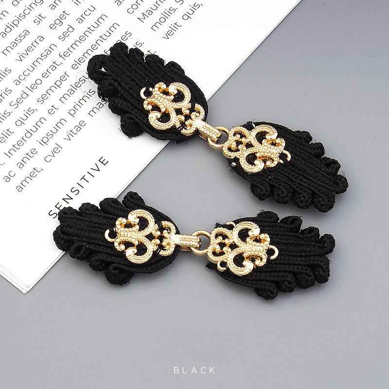 Black Chinese frog button pair with gold ornate clasp, braided tassels, toggle closure