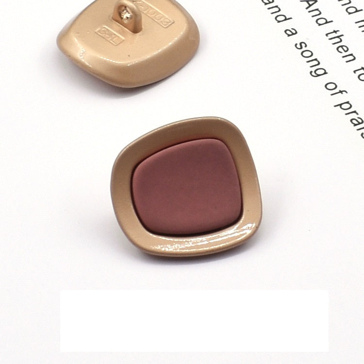 Square concave metal shank button, mauve/purple front with gold-tone frame