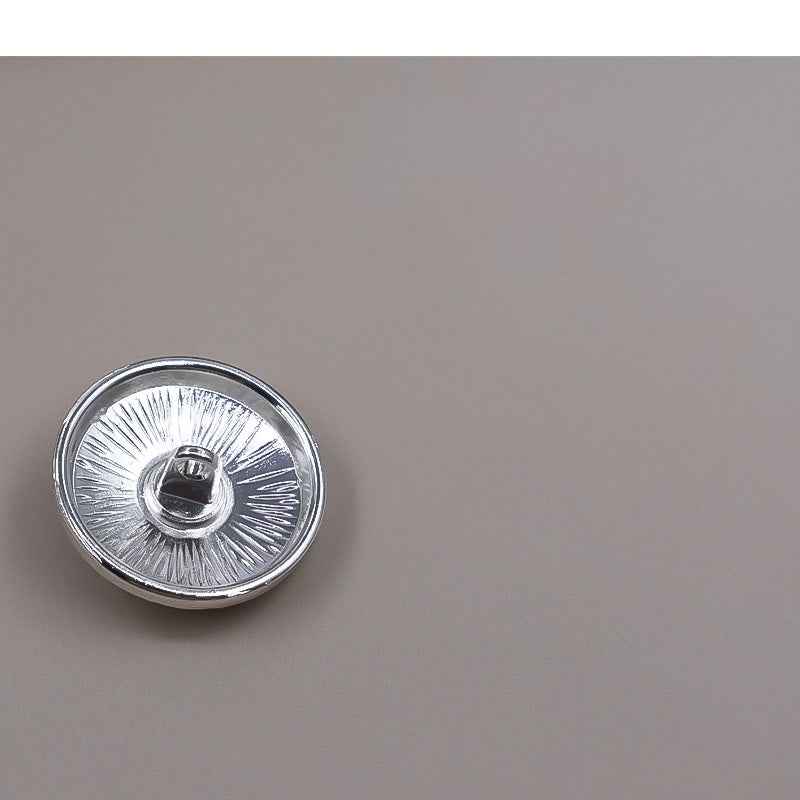 Silver round metal shank button with radial ridges, back view