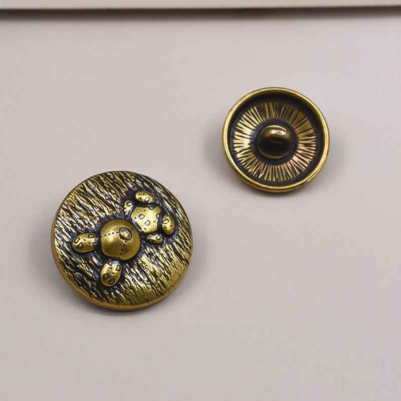 Gold round metal shank button with radial ridges, back view