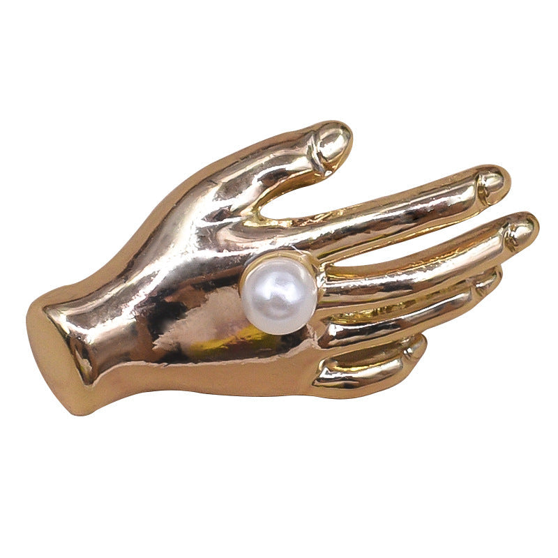 Gold metal palm-shaped pearl button with white pearl center, close-up