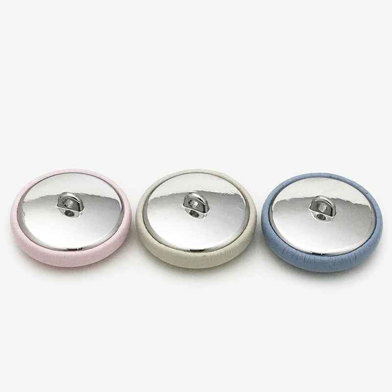 Button backs with metal shanks—pink, beige, and blue fabric-covered rounds.