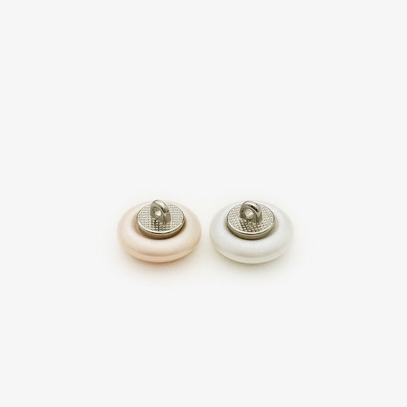 Metal-backed pearl sew-on buttons, underside close-up of two buttons
